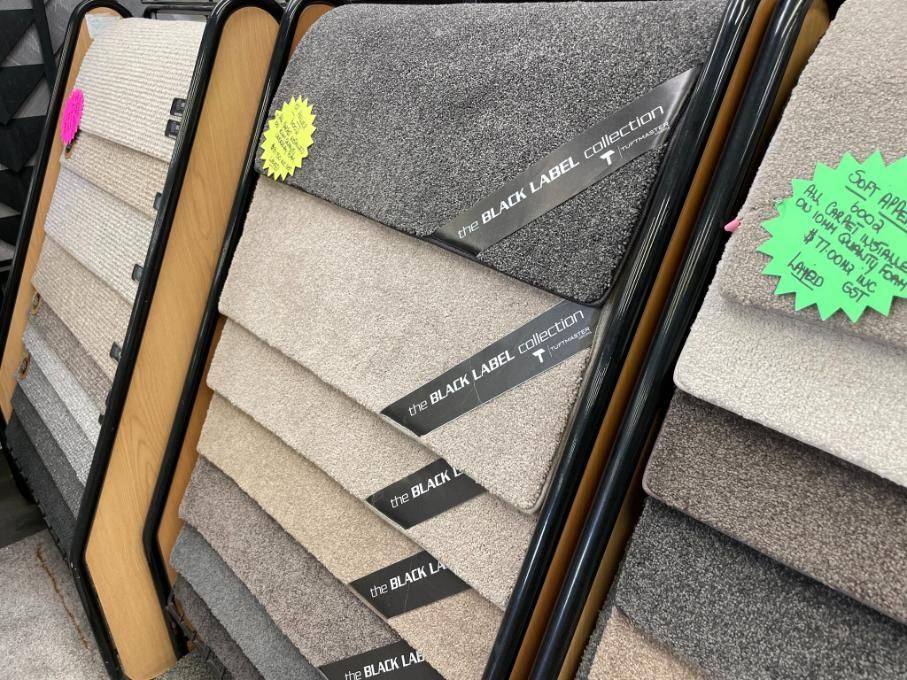 A Display of Carpets in a Store With a Green Sign — Traditional Tiles & Flooring in Port Douglas, QLD