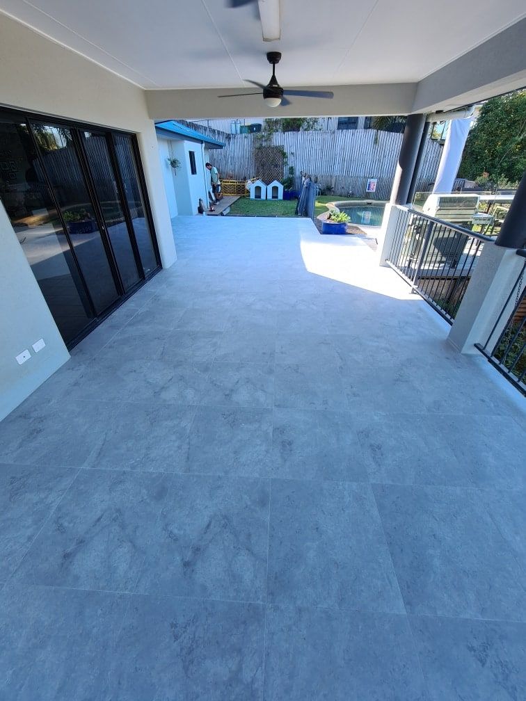 A Large Patio with A Ceiling Fan and Sliding Glass Doors — Traditional Tiles & Flooring In Woree, QLD