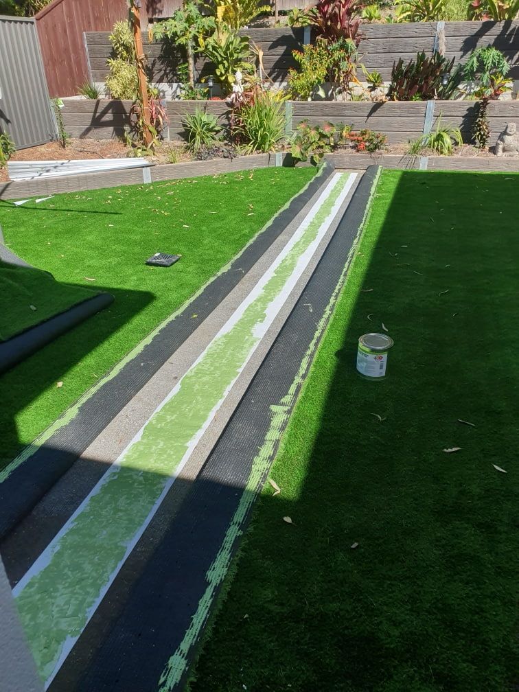 A Lawn with A Black and White Stripe on It Is Being Installed in A Backyard — Traditional Tiles & Flooring In Woree, QLD