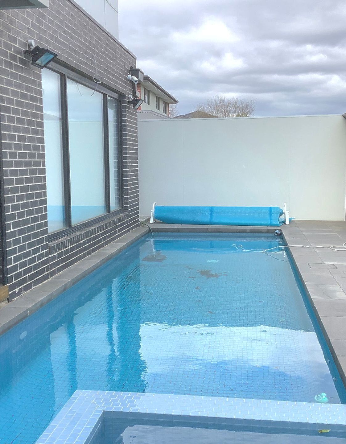 A blue skimmer is sitting on the edge of a swimming pool.