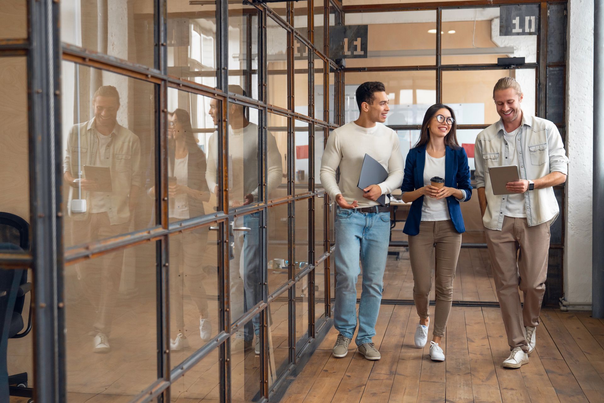A group of people are walking down a hallway in an office.