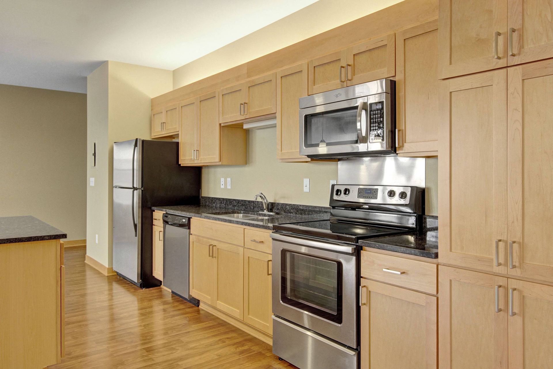 Kitchen with light wood cabinets, stainless steel appliances, and hardwood floors.