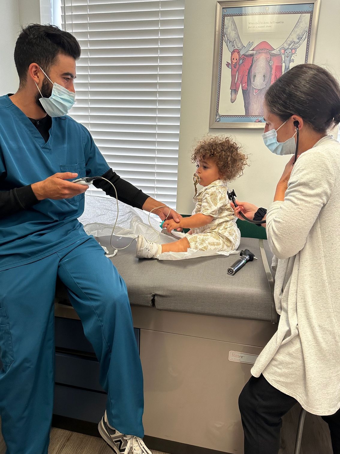A doctor is examining a baby while a woman looks on.