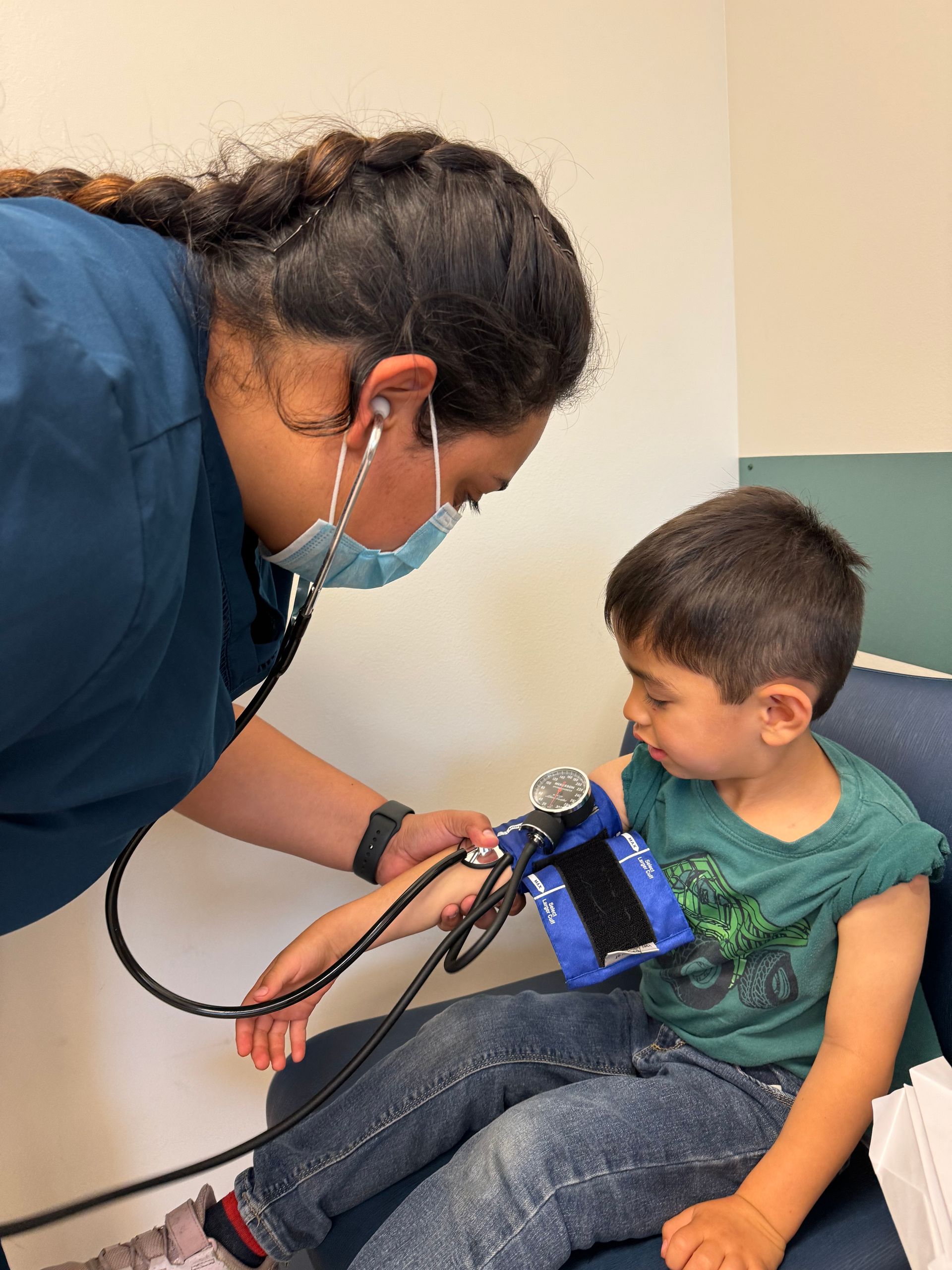 Medical professional taking blood pressure of young boy.