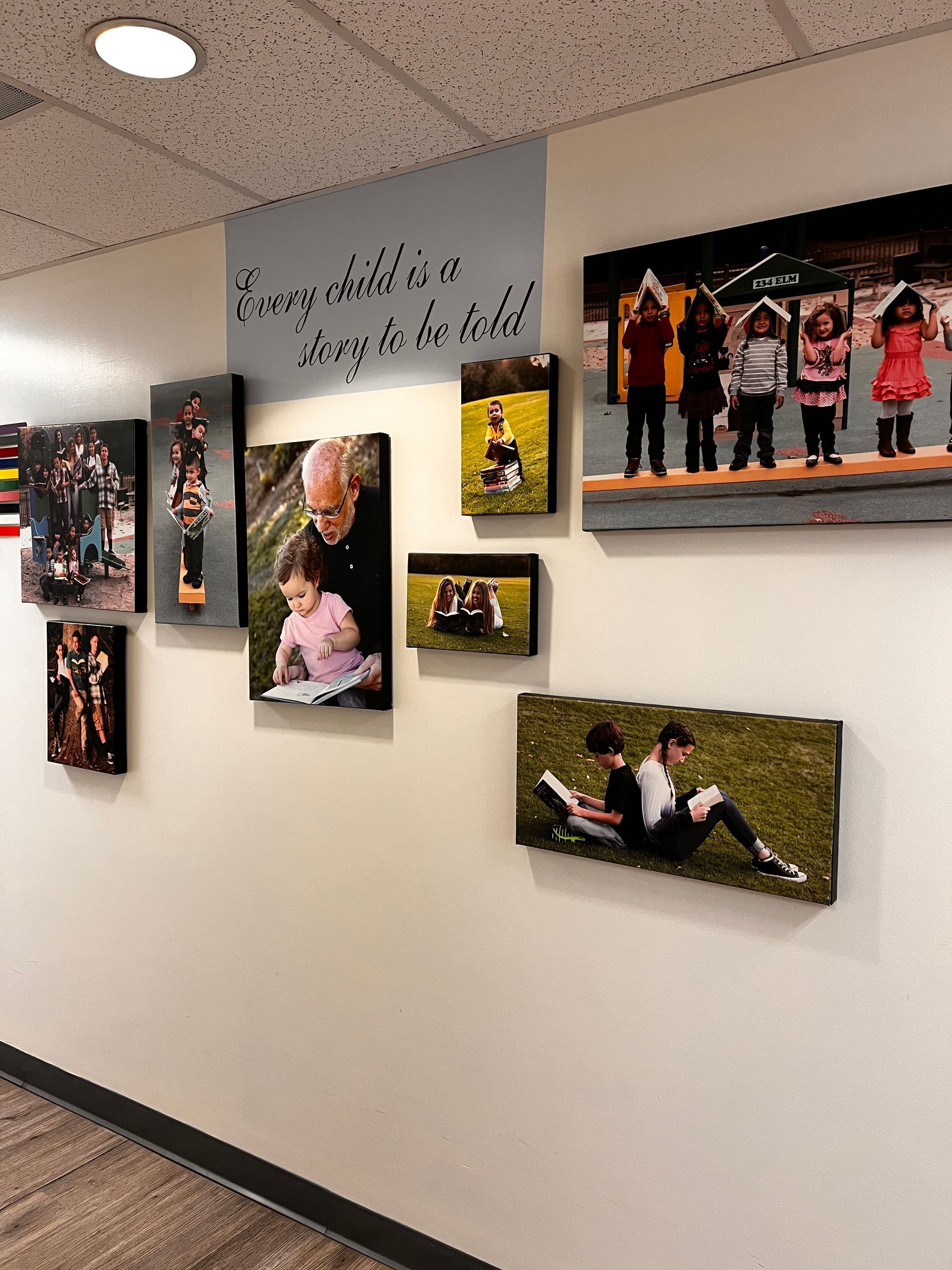 A hallway with pictures on the wall and a sign that says `` every child is a gift to be held ''