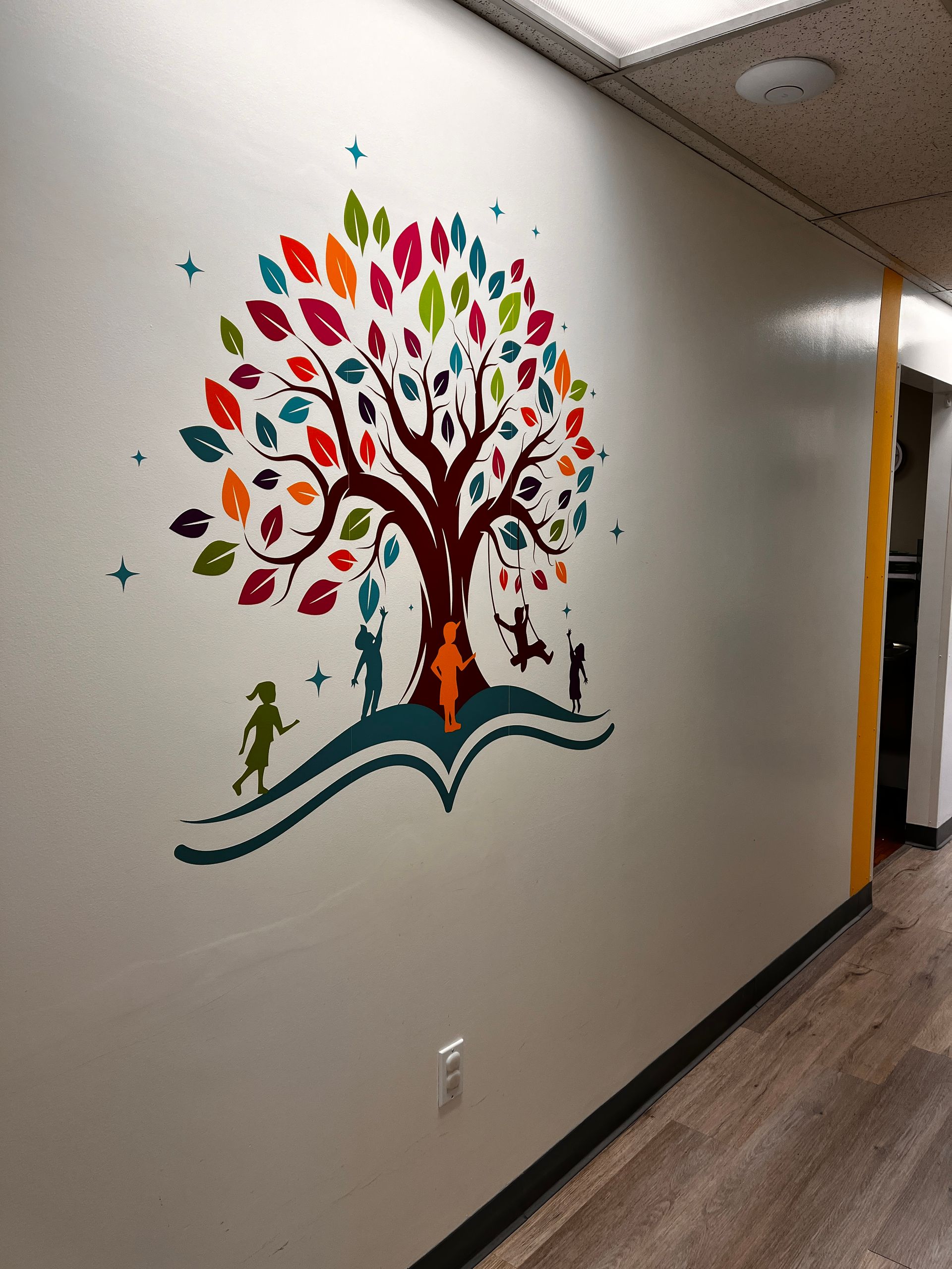 A hallway with a painting of a tree on the wall.
