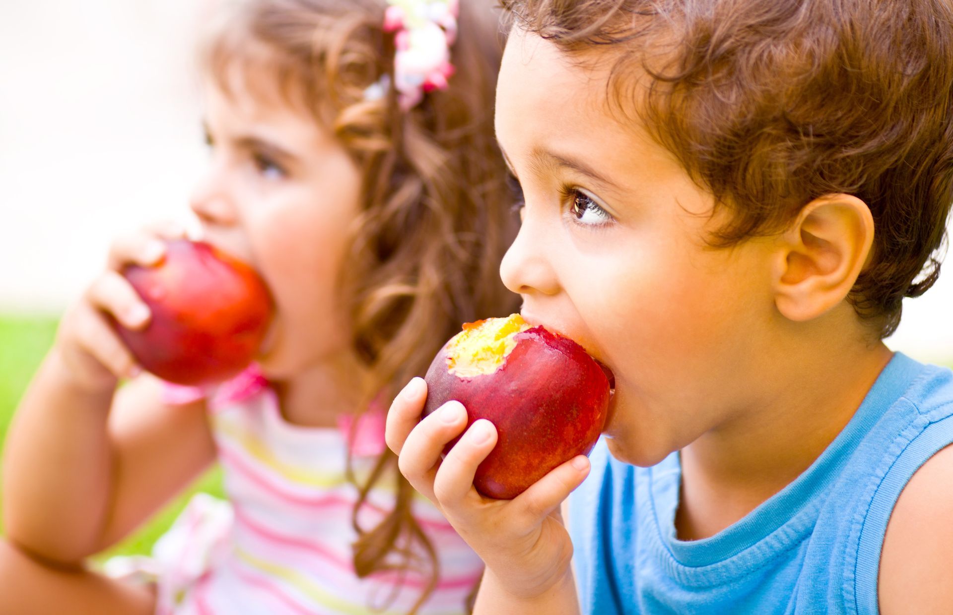 A boy and girl are eating apples