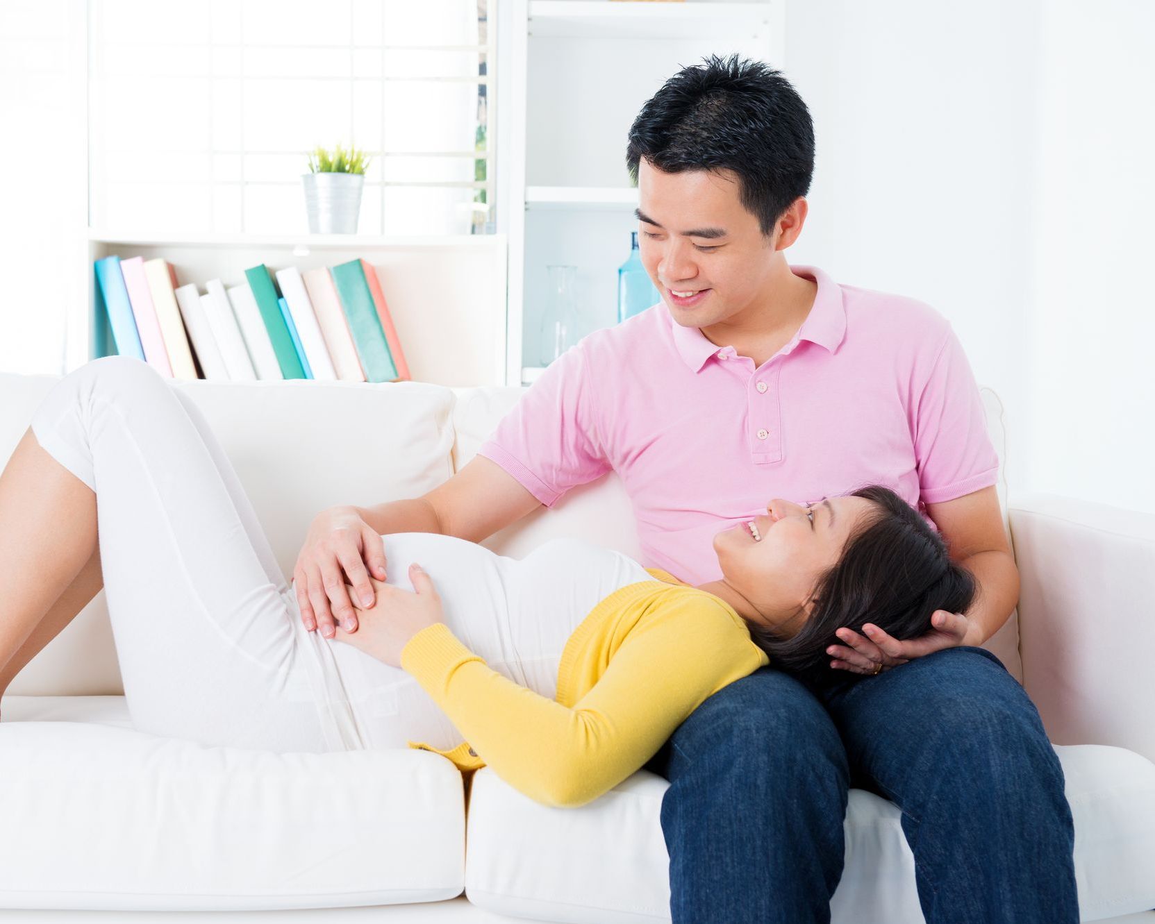 A man and pregnant woman are sitting on a sofa