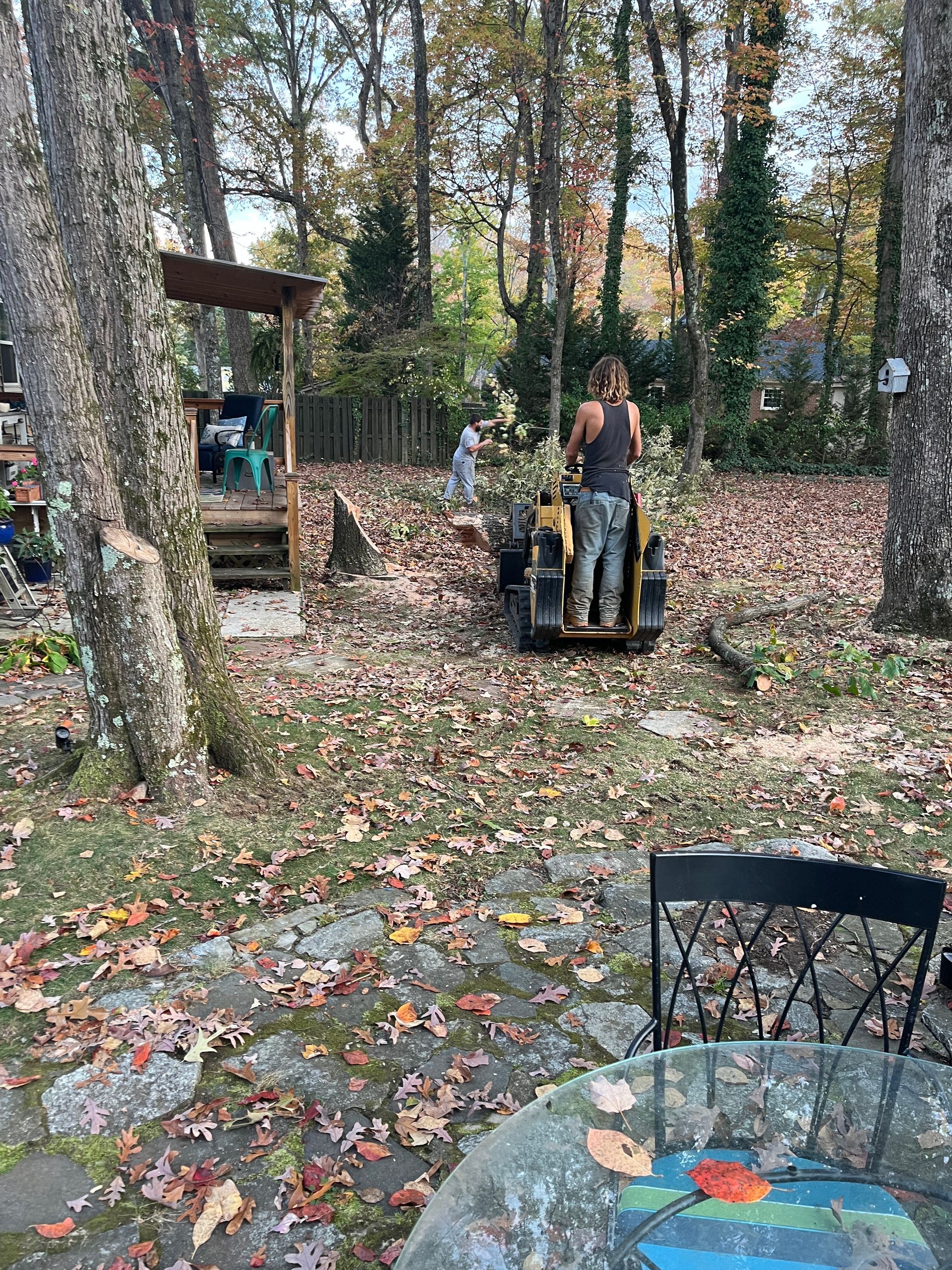 A woman is riding a tractor in a backyard.