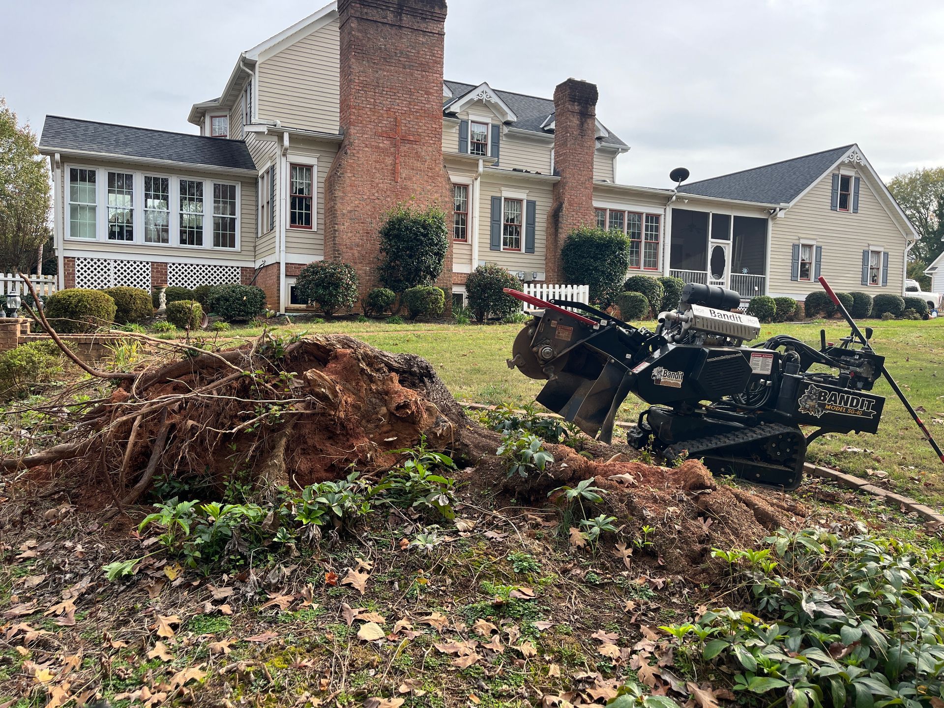 A stump grinder is sitting in front of a large house.