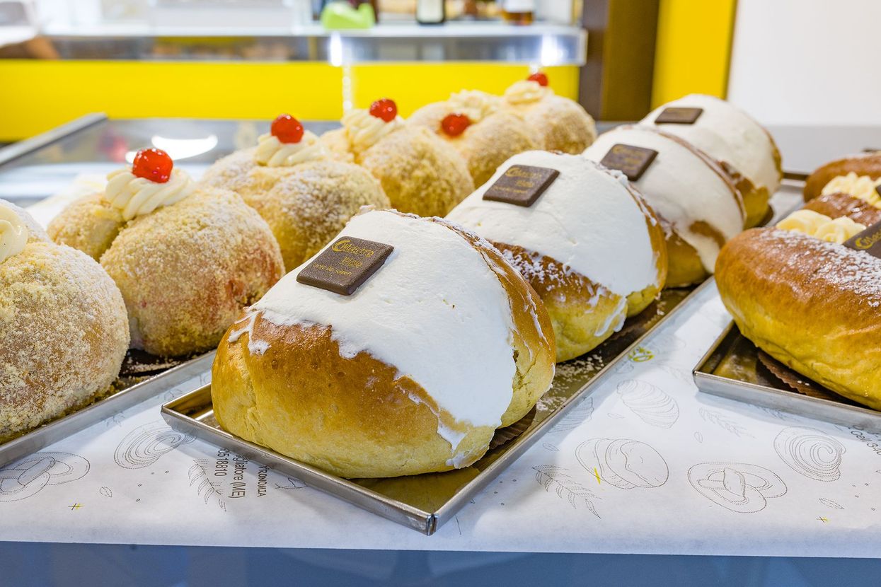 Assortimento di pasticcini e dessert ripieni di crema, esposti su un vassoio da pasticceria.