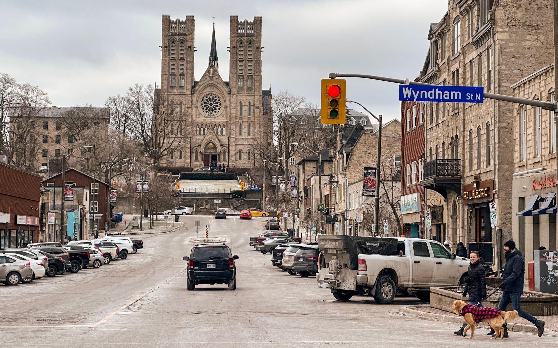 A man is walking a dog down a street in front of a large church.