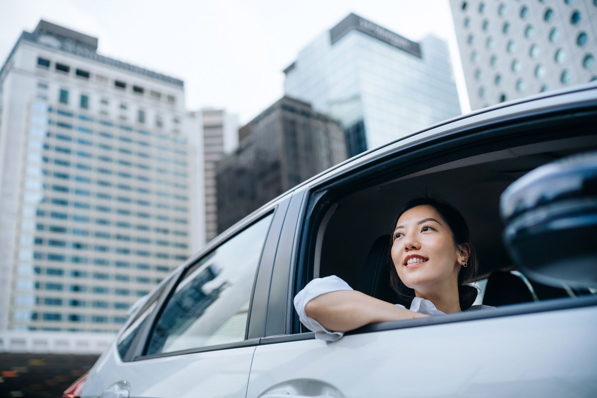 Smiling woman looking out of her car window, enjoying peace of mind with quality car insurance in El