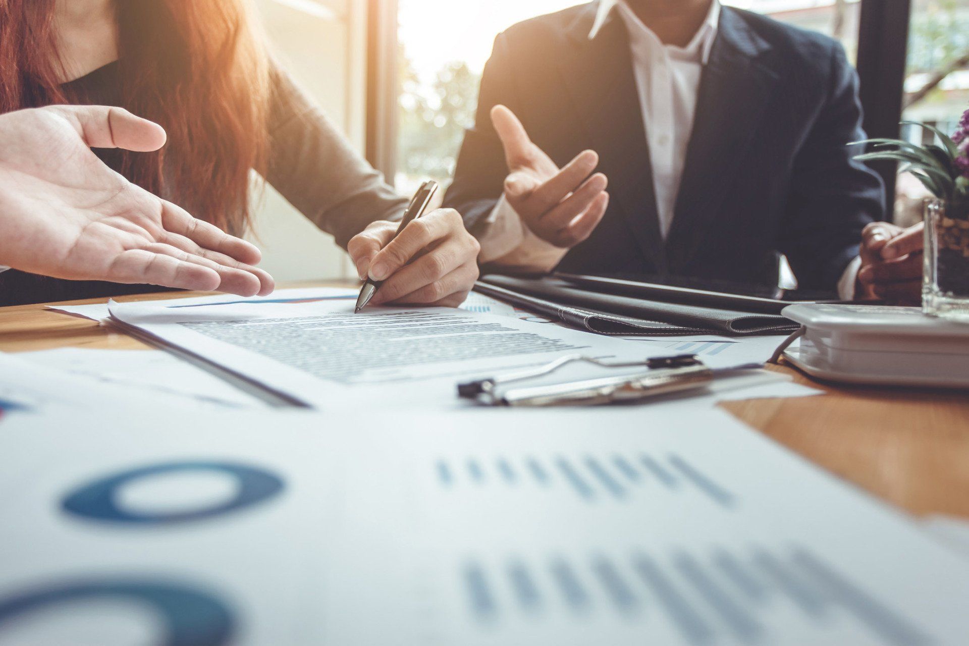 Three business people reviewing documents at a table, one person signing a paper.