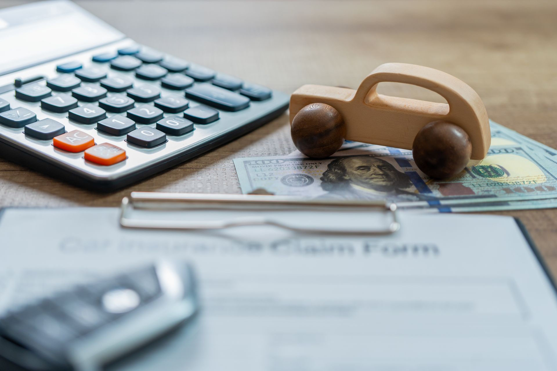 Auto insurance concept with calculator, money, car keys and car toy on wood table.]