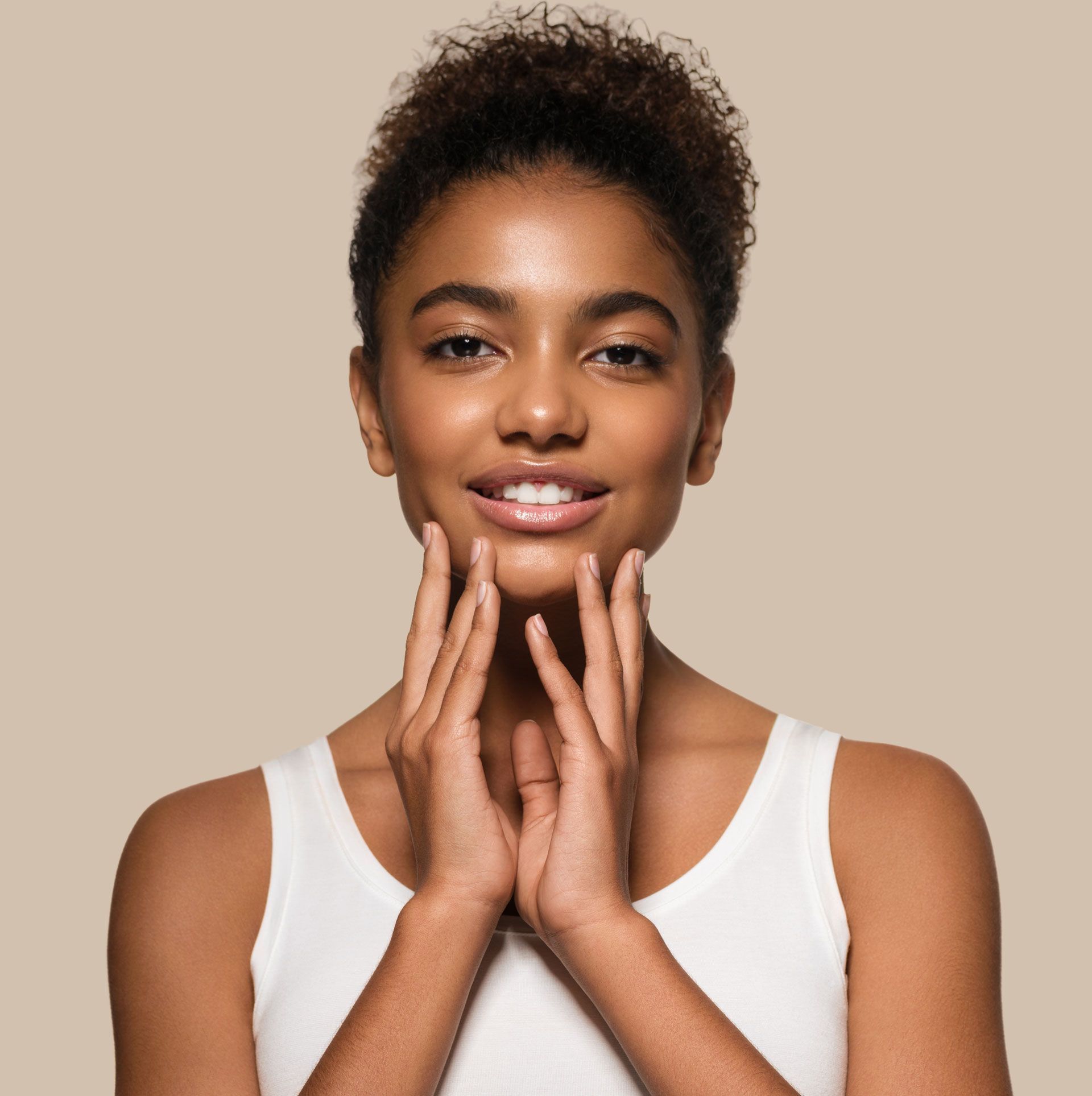 A woman is touching her face with her hands and smiling.