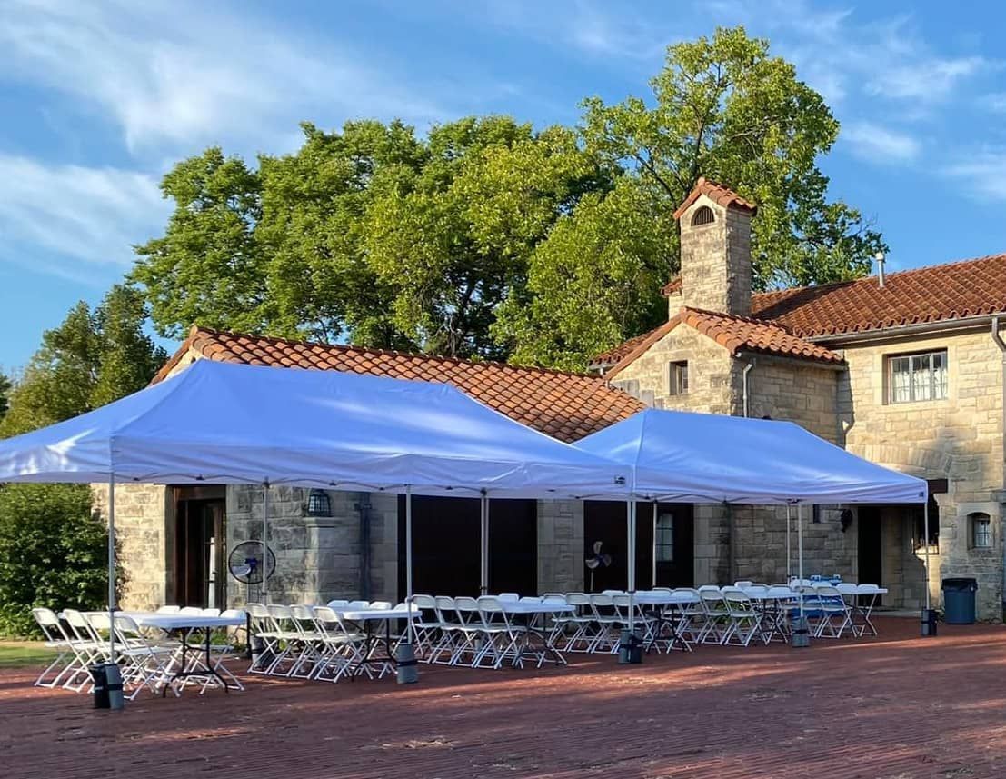 a large stone building with a lot of tents and chairs in front of it .