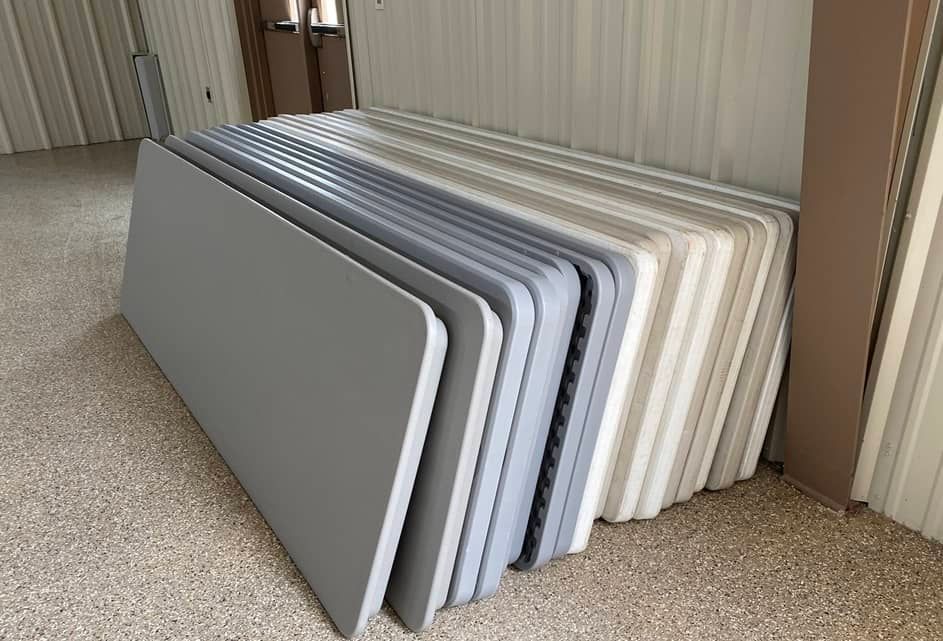 a stack of folding tables sitting on top of each other on the floor .