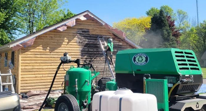 A green machine is cleaning the side of a house.