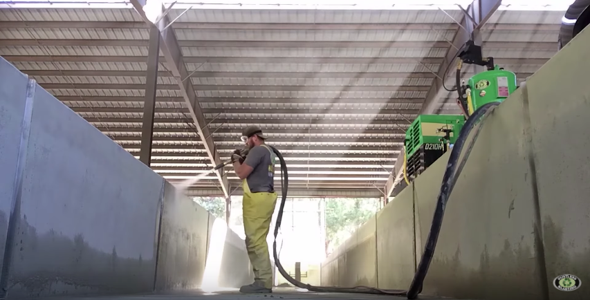 A man is spraying a wall with a high pressure washer.