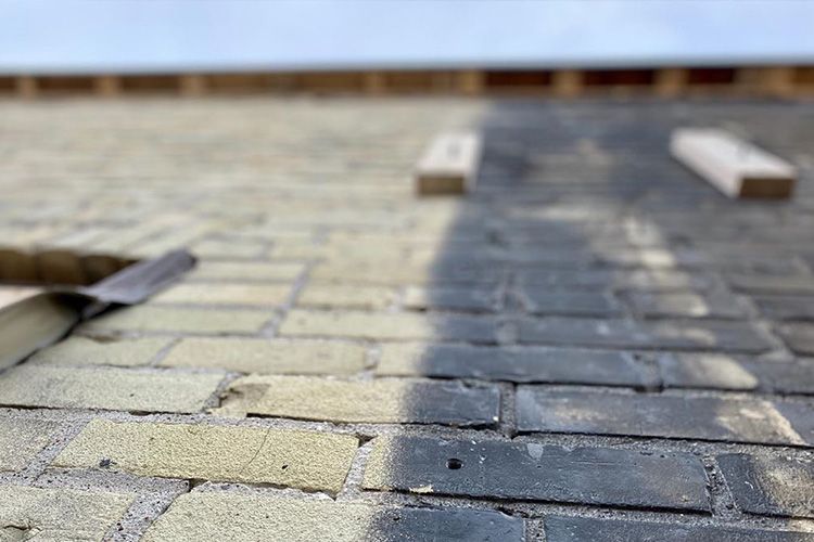 A close up of a brick walkway being built on a roof.