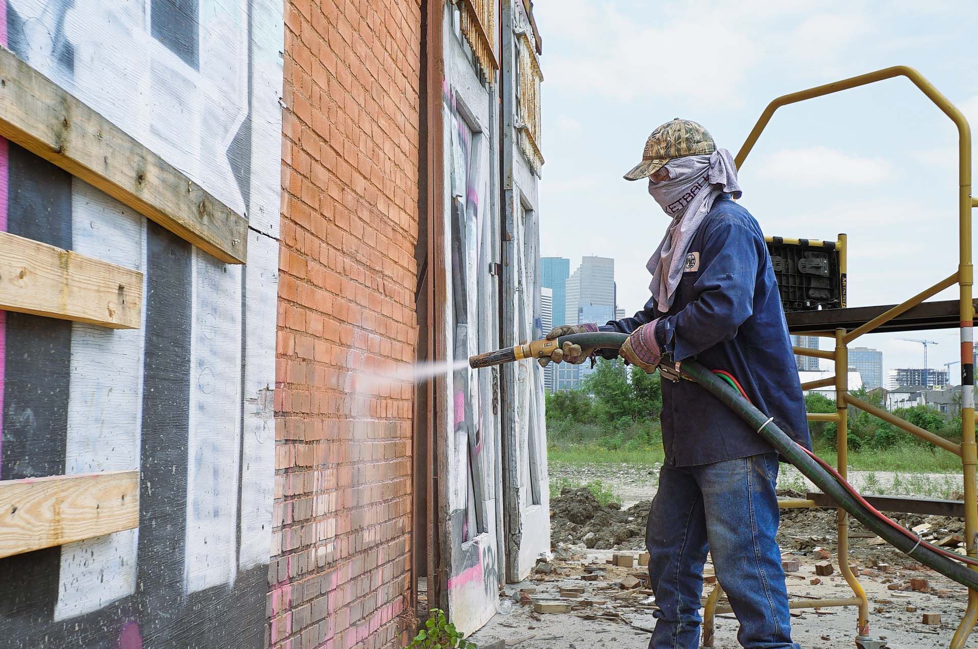 A man is spraying paint on a brick wall.