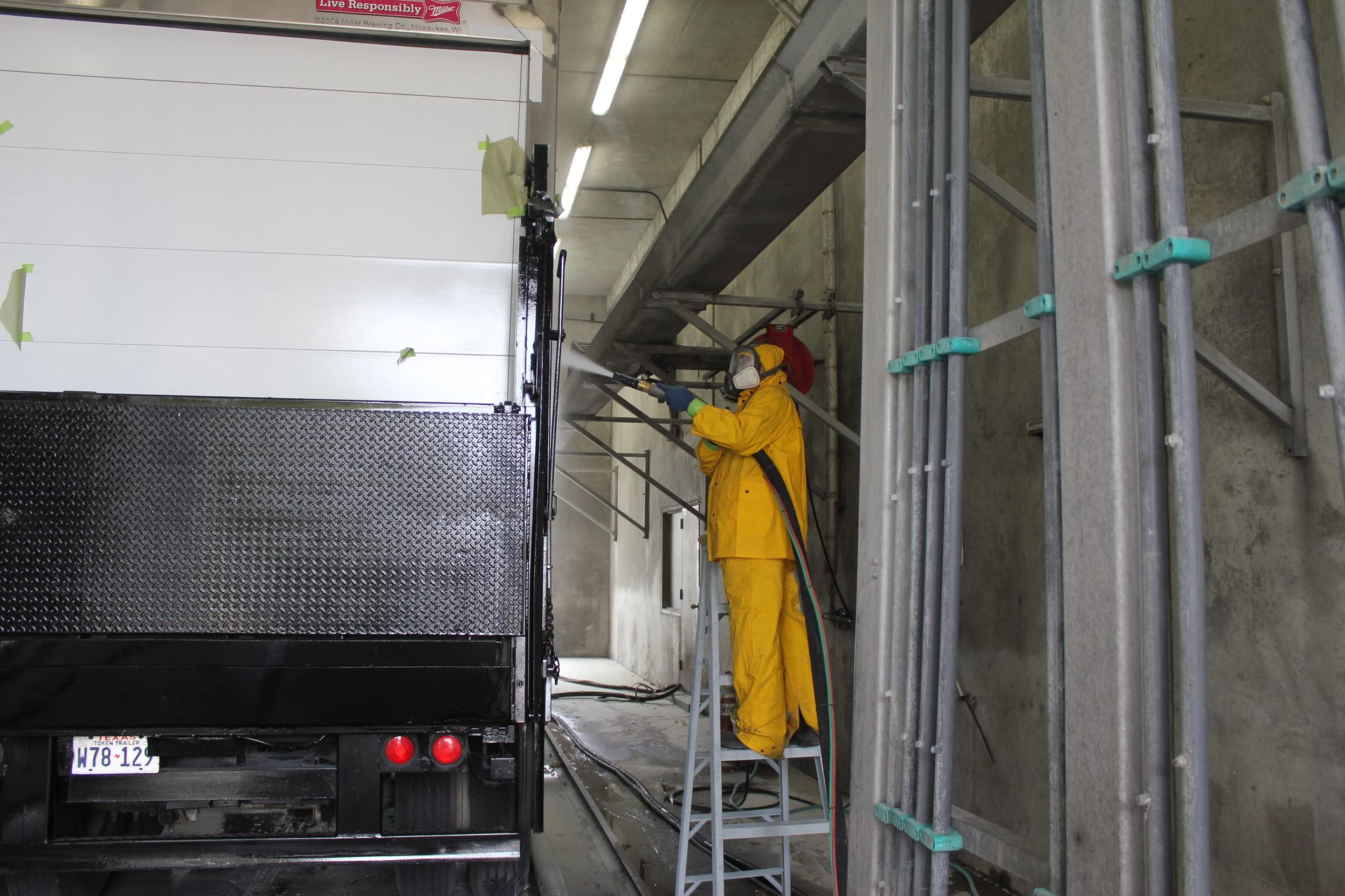 A man in a yellow suit is standing on a ladder in front of a truck.