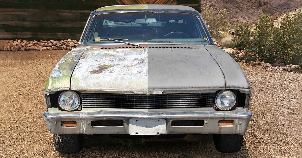 A silver car is parked on a gravel road.