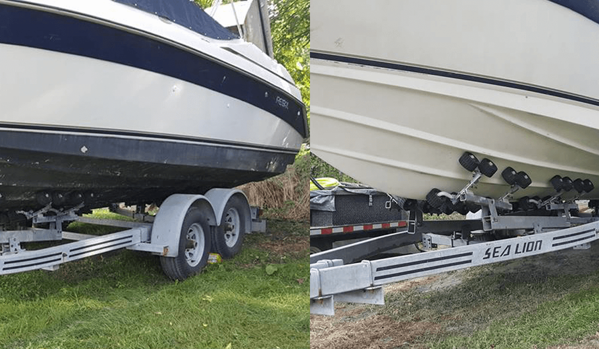 A boat is sitting on a trailer in the grass.