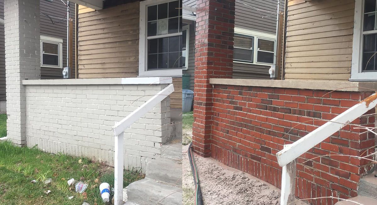 A brick house with stairs leading up to it and a white railing.