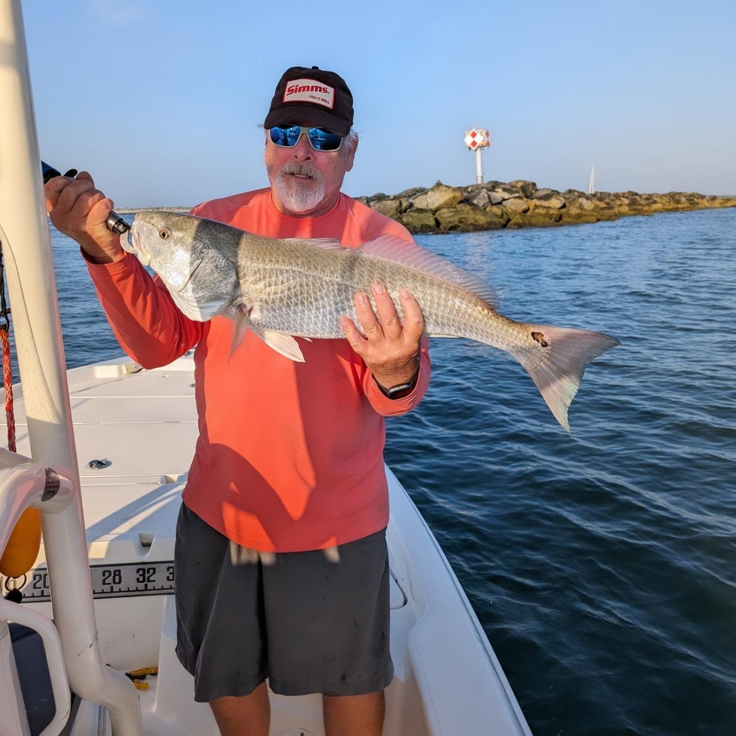 A man standing on a boat holding a large fish
