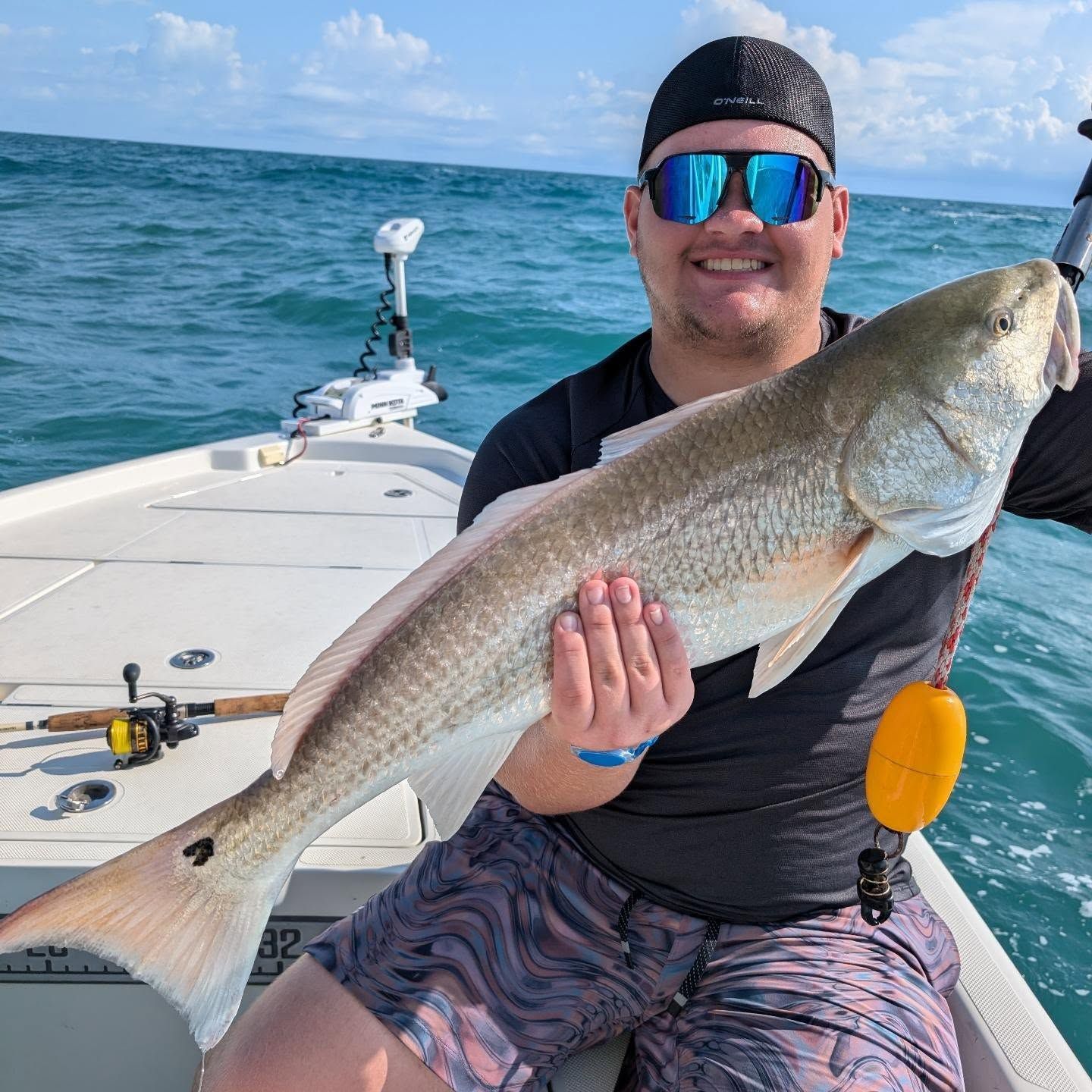 A man is sitting on a boat holding a large fish.