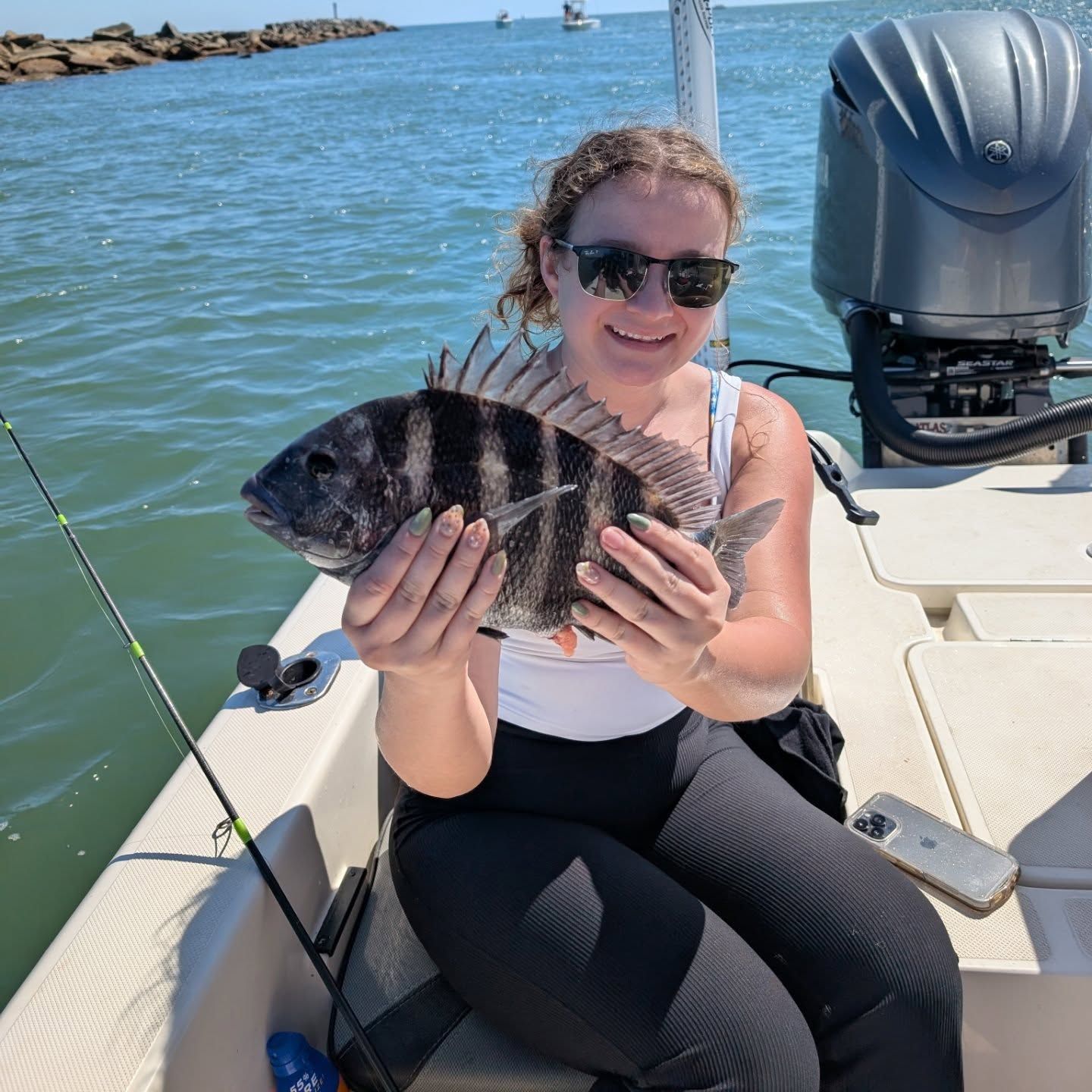 A woman is sitting on a boat holding a fish.