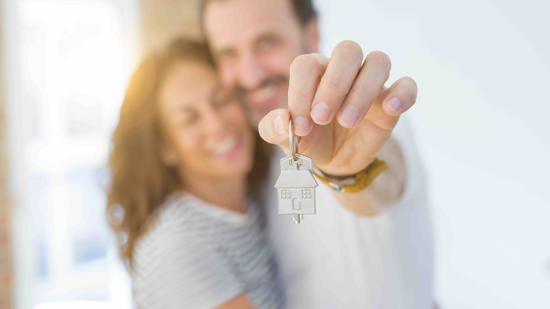 a man is holding a house key in front of a woman.