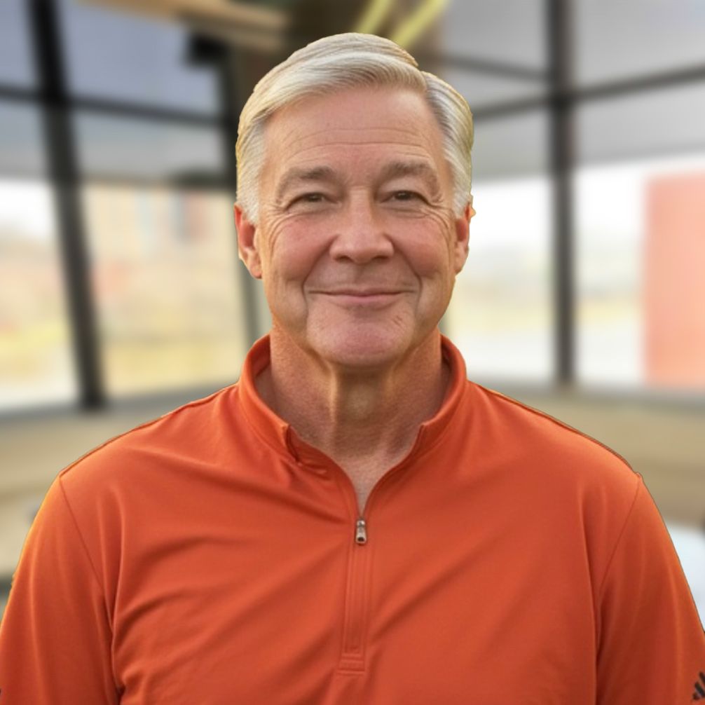 Fred Smith is wearing an orange Adidas shirt and smiling for the camera.