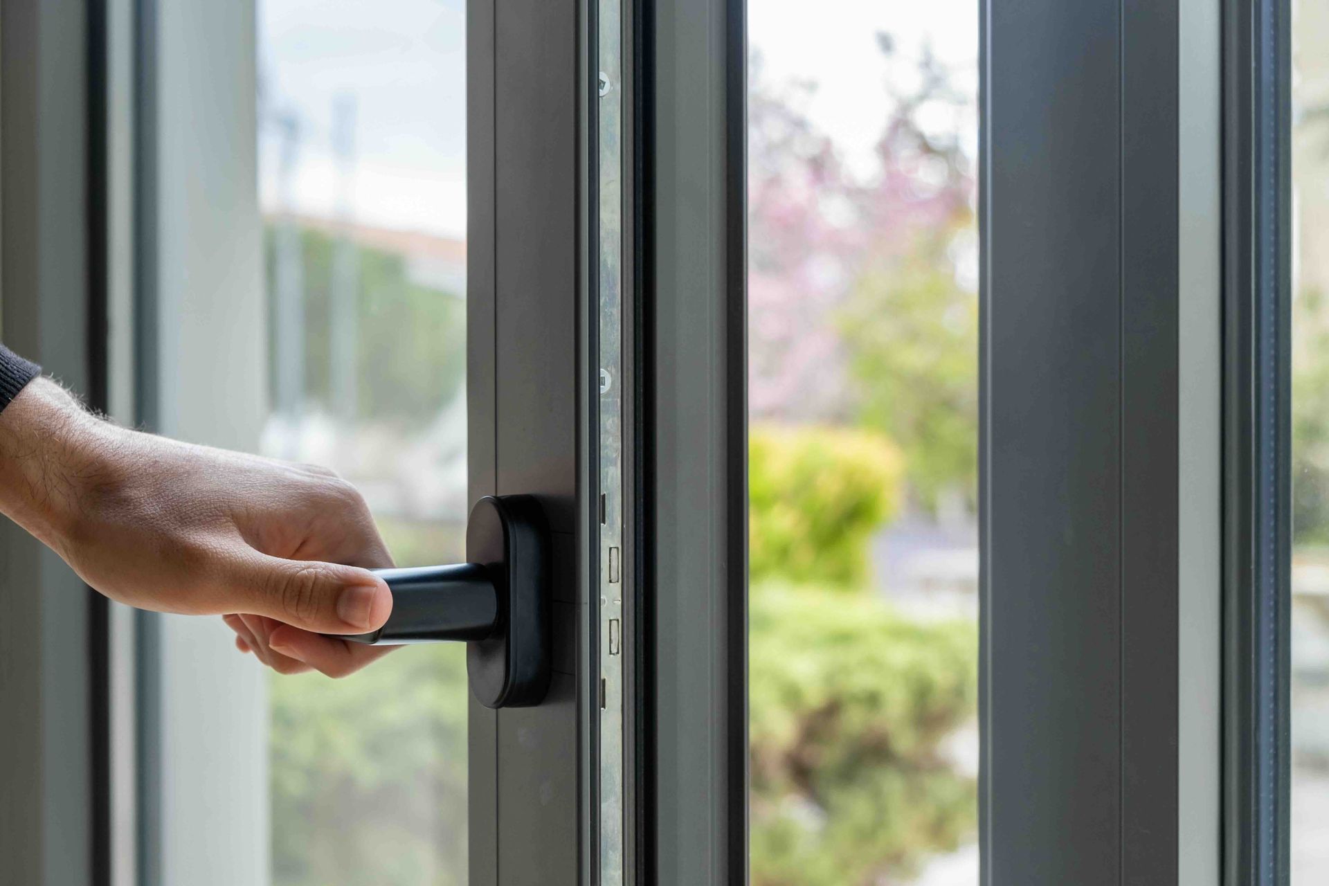 A person is opening a glass door with a black handle.