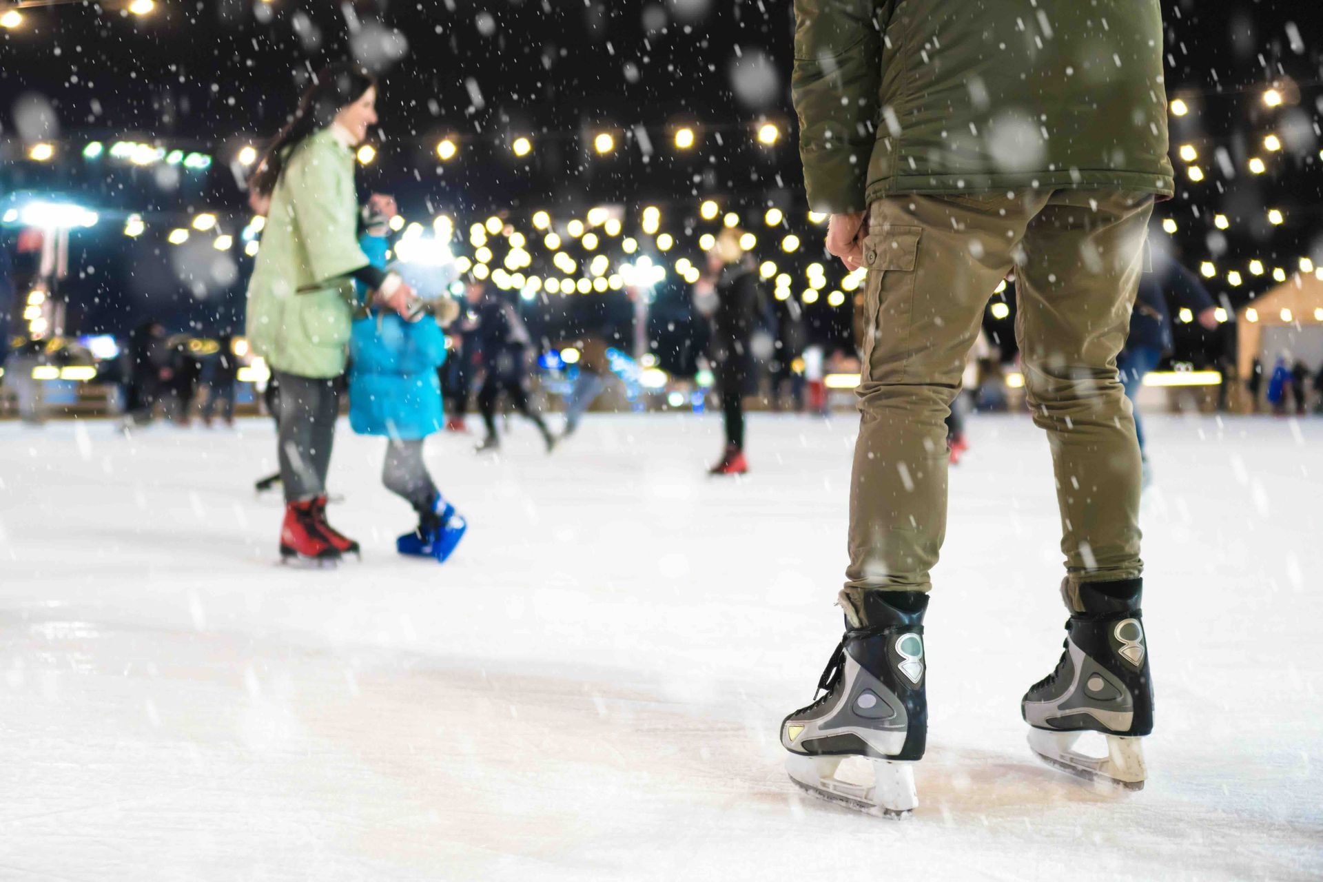 A group of people are ice skating on a rink at night.