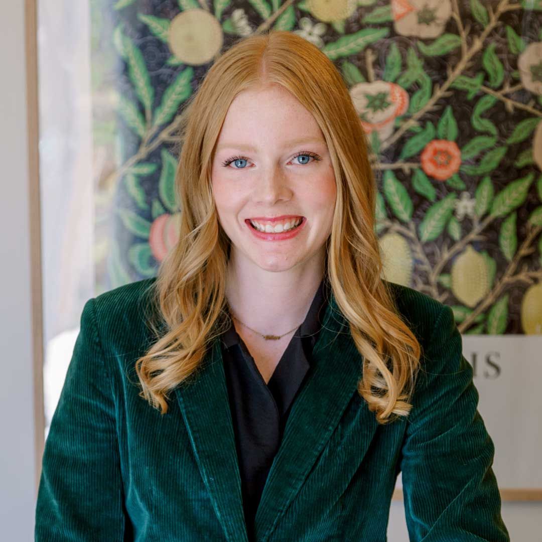 Jillian Bartels with long blonde hair, smiling, wearing a black shirt and green velvet blazer.