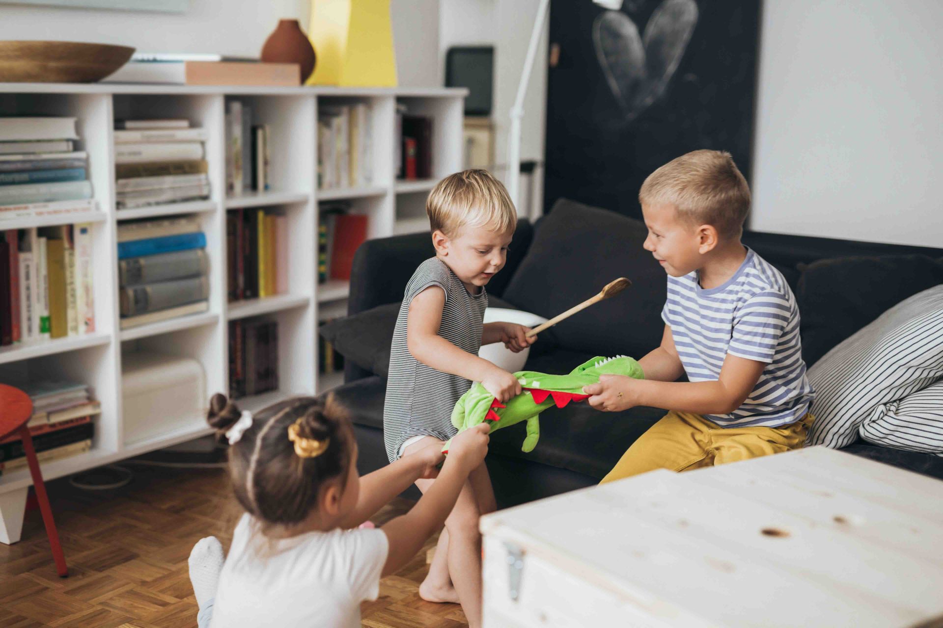 Three children are playing with a toy in a living room.