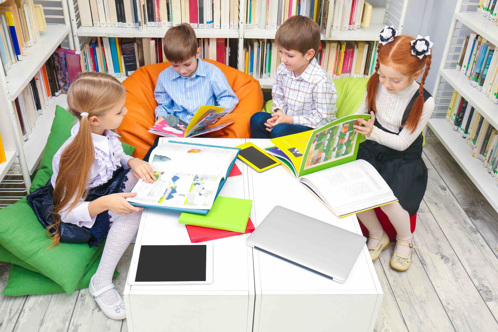 A group of children are sitting around a table in a library reading books.