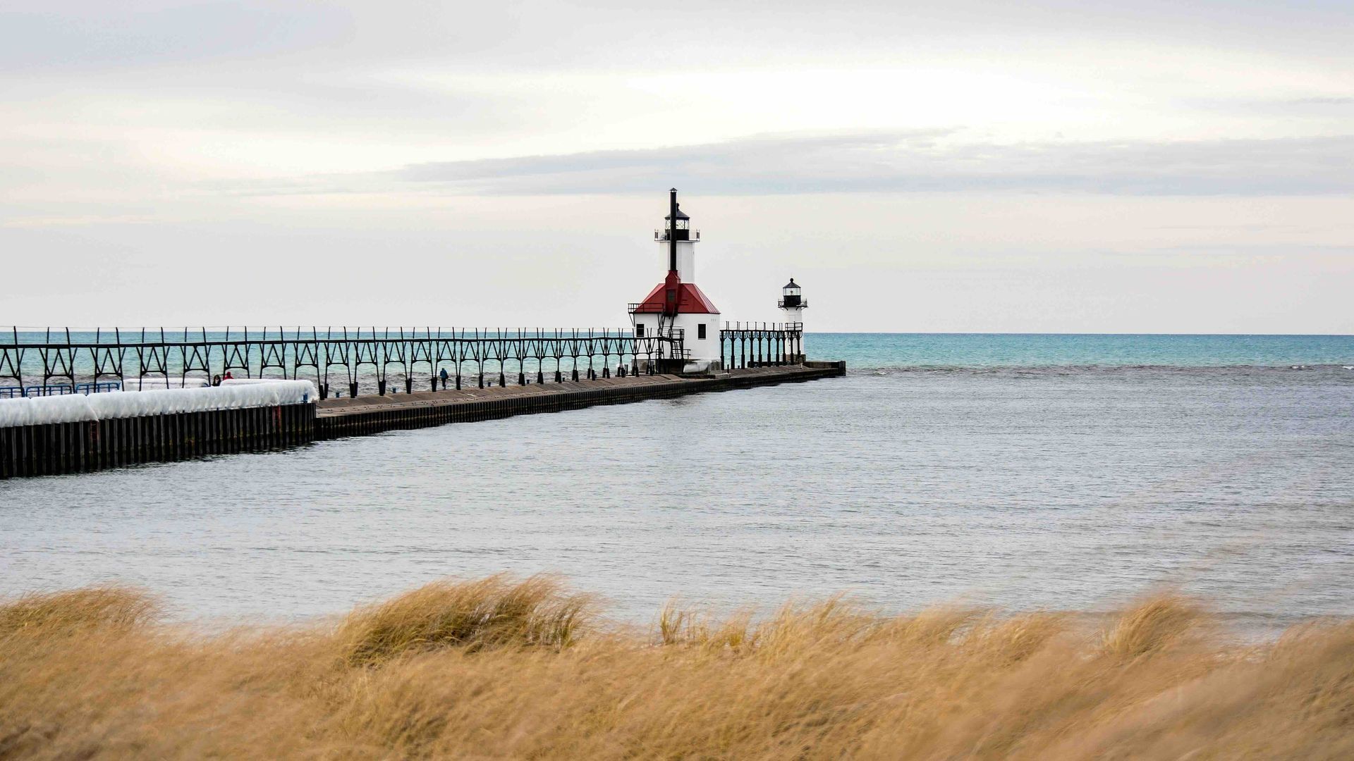 a lighthouse is sitting on top of a pier on the shore of lake michigan.