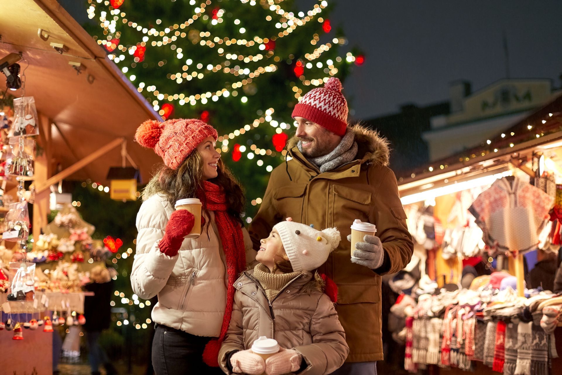 A family is standing in front of a Christmas tree at a Christmas market.