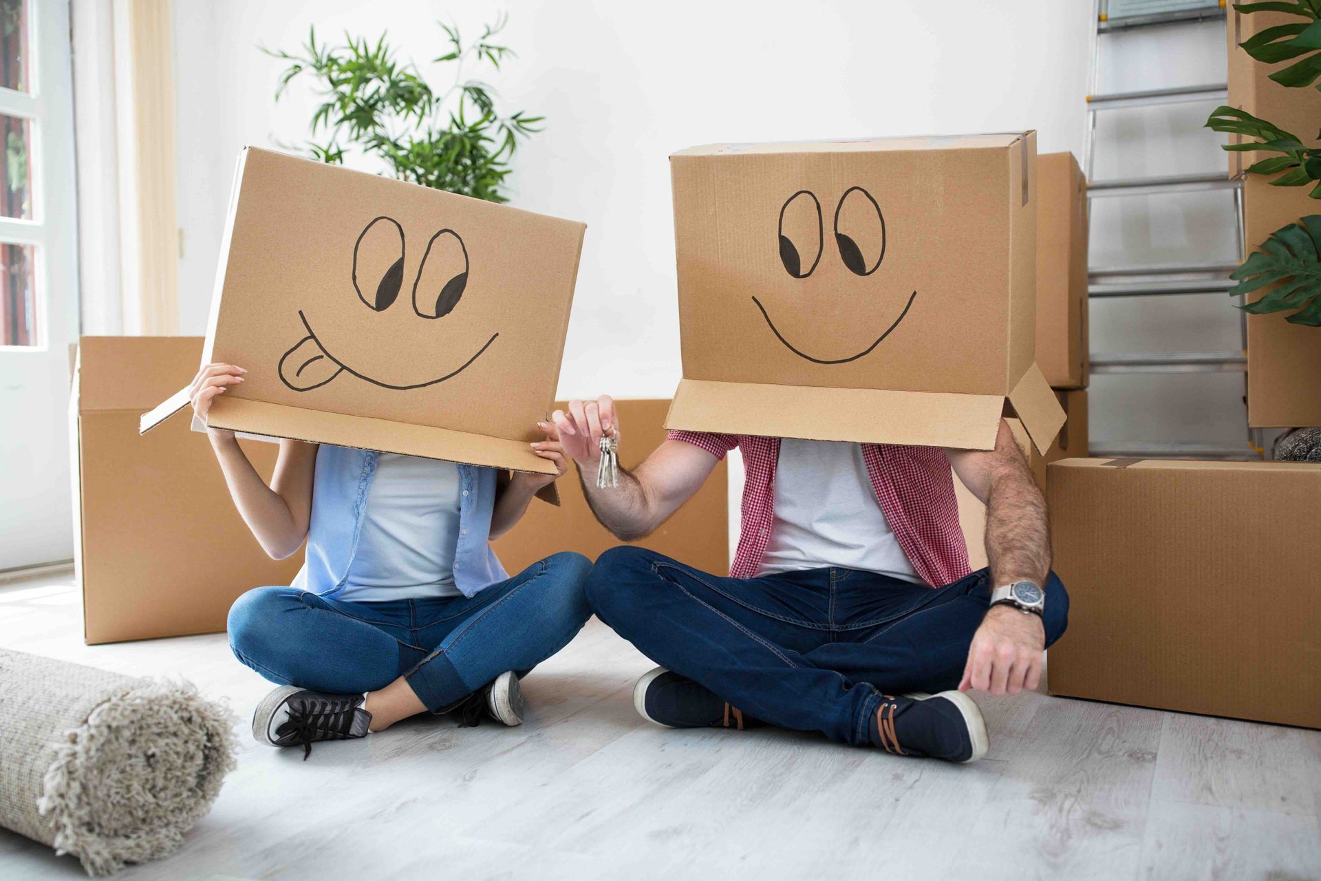 A man and a woman are sitting on the floor with cardboard boxes on their heads.