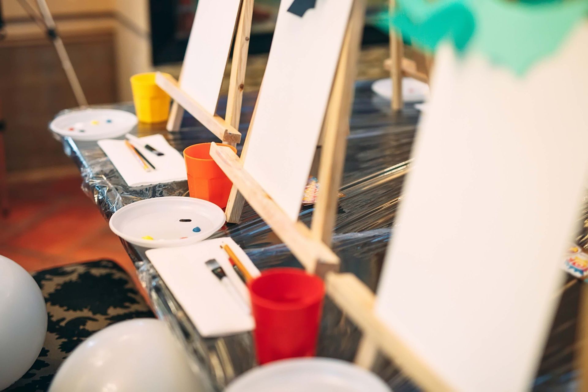 A table with painting easels , plates , cups and brushes on it.