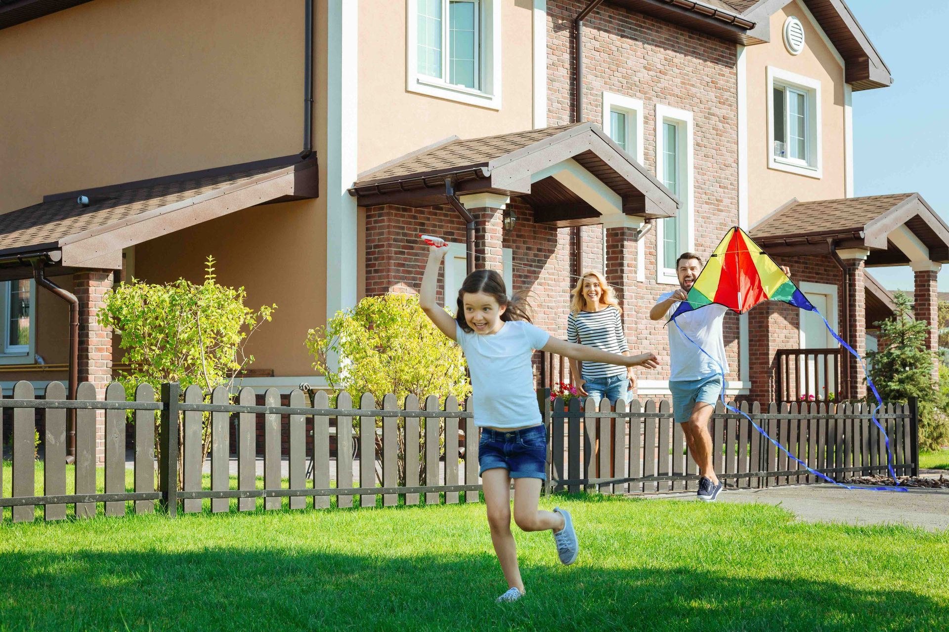 A family is flying a kite in front of their house.