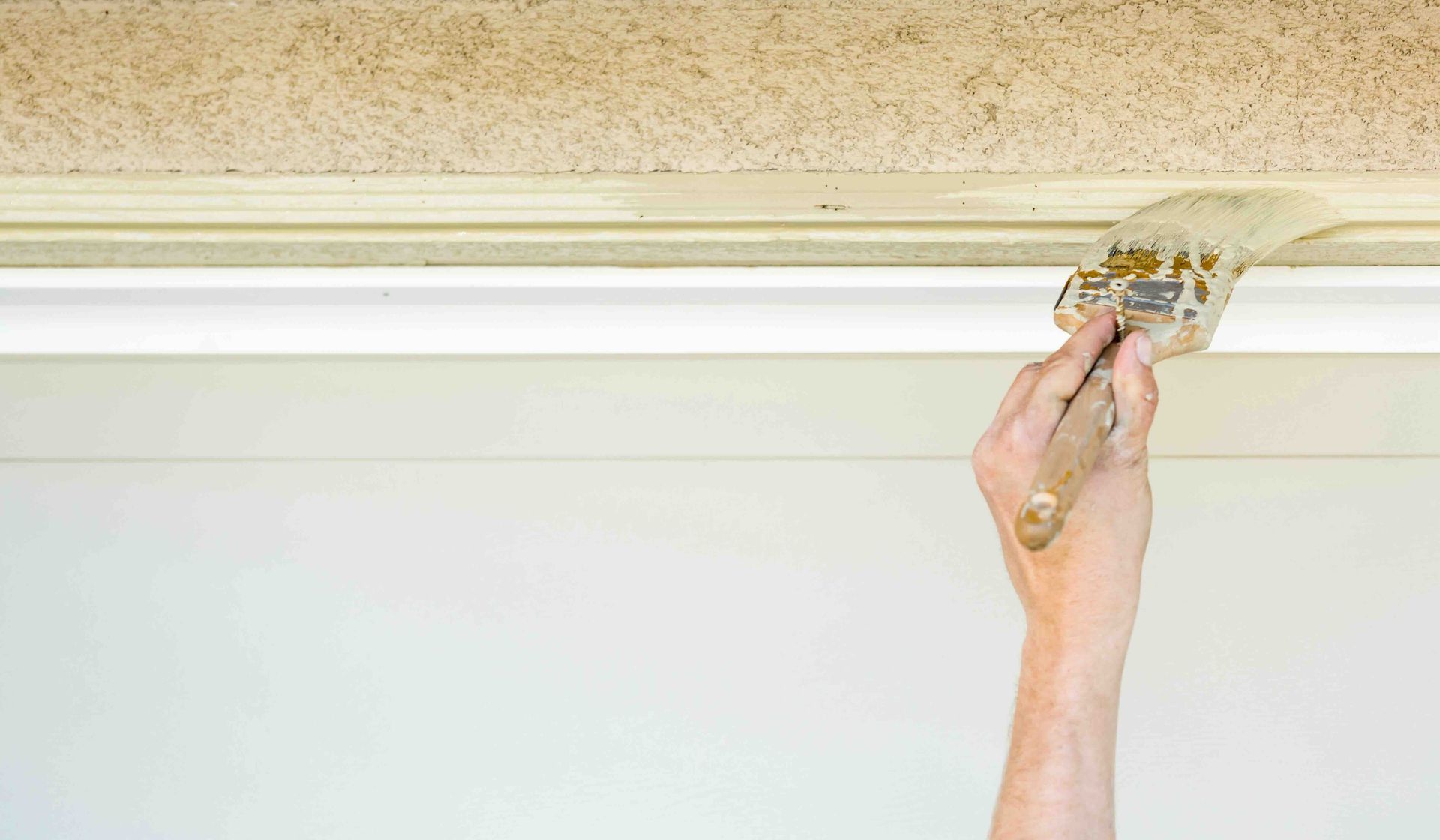 A person is painting trim with a brush.