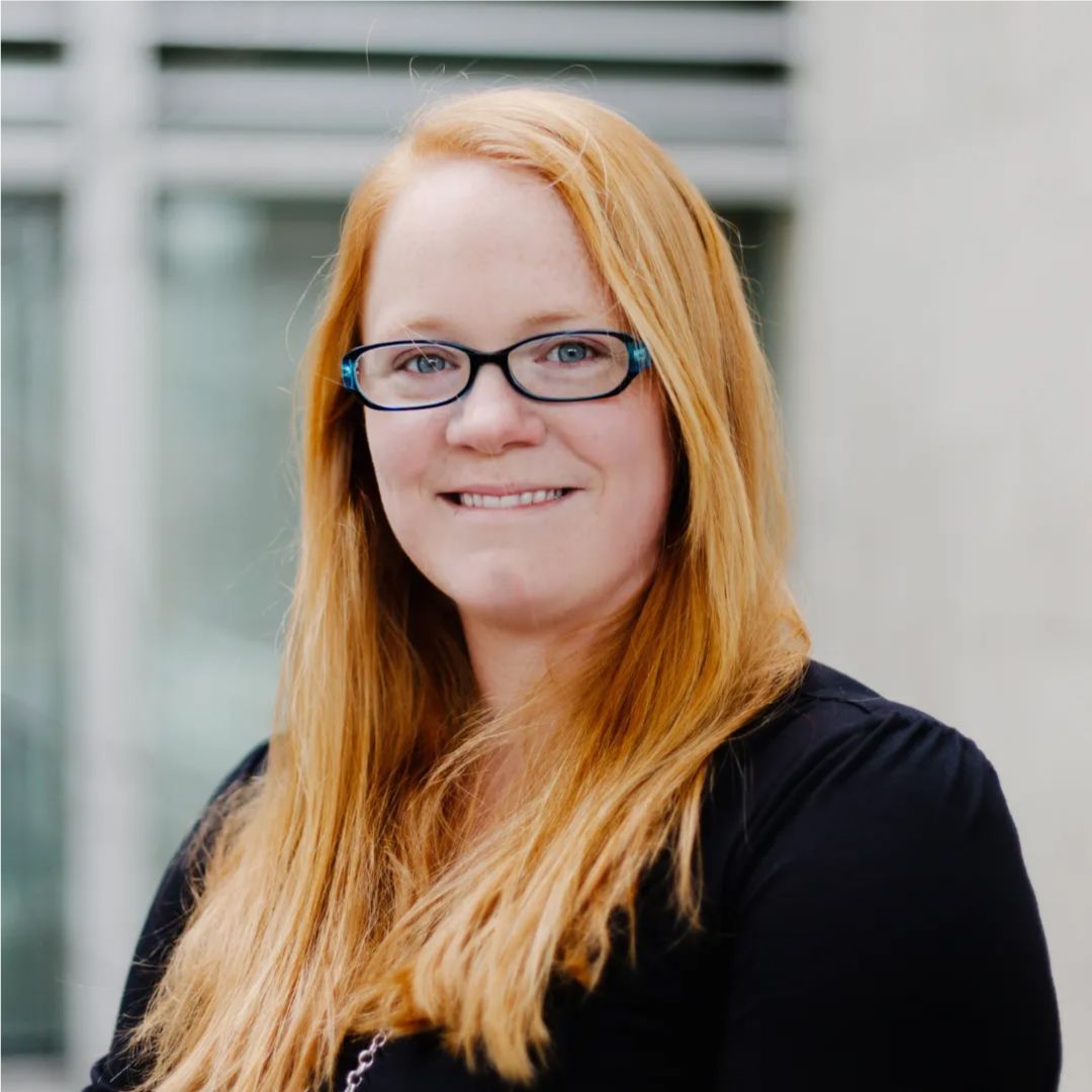 Tabrina Conway with long red hair wearing glasses and a black shirt