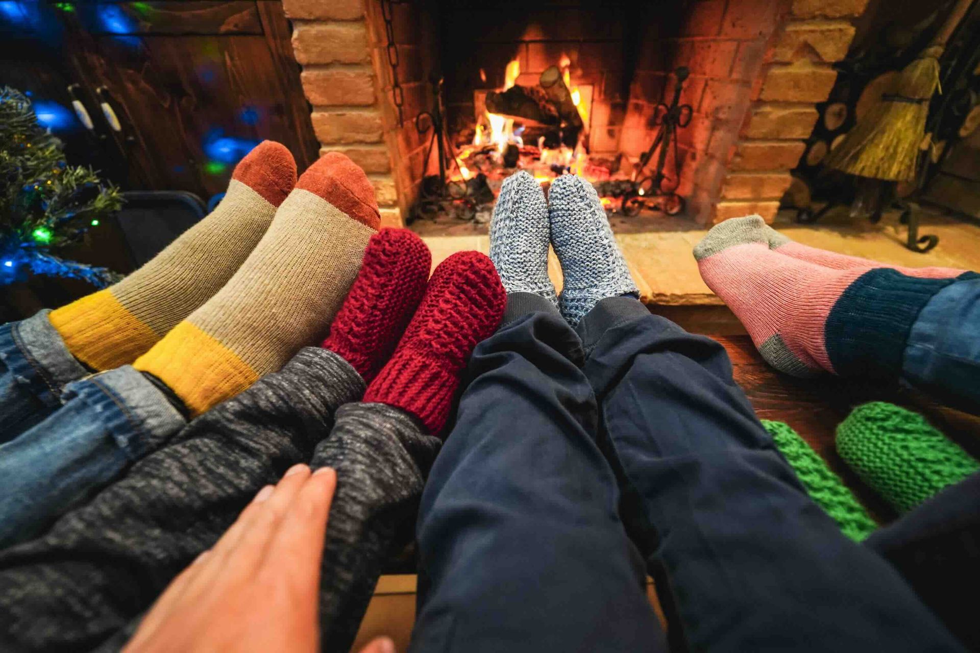 A group of people are sitting in front of a fireplace wearing socks.