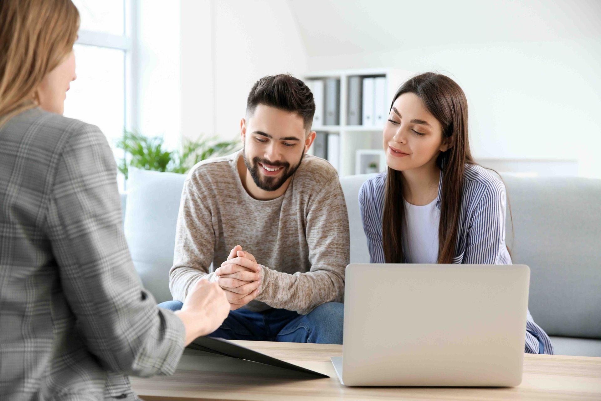 A man and a woman are sitting on a couch looking at a laptop.