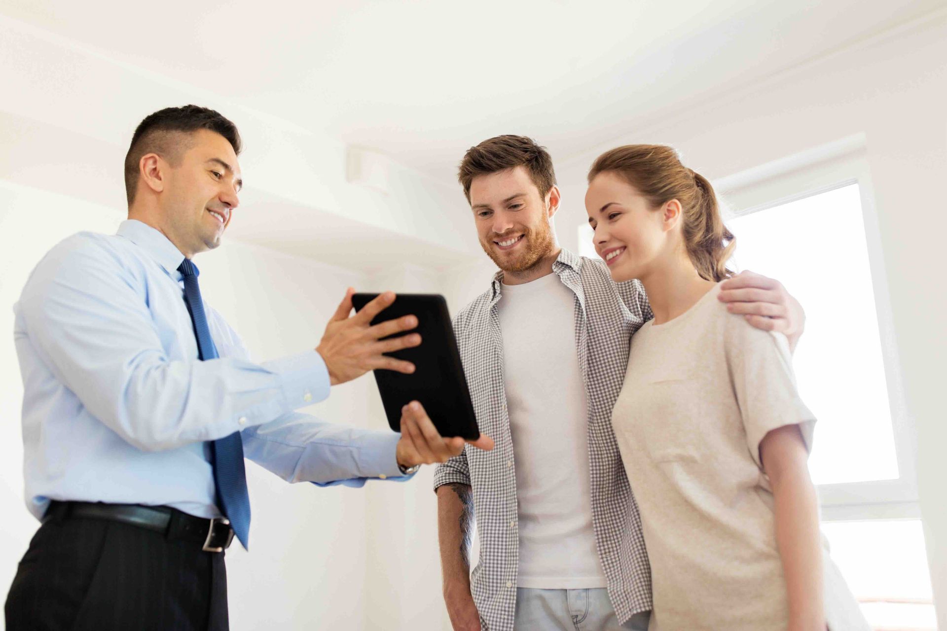 A man is holding a tablet in front of a couple.